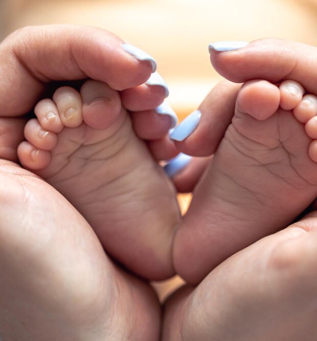 mom gently holding her baby's feet showing recovery from hand-foot-and- mouth disease