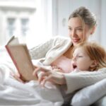 Mother reading to her daughter in bed to establish a healthy sleep routine