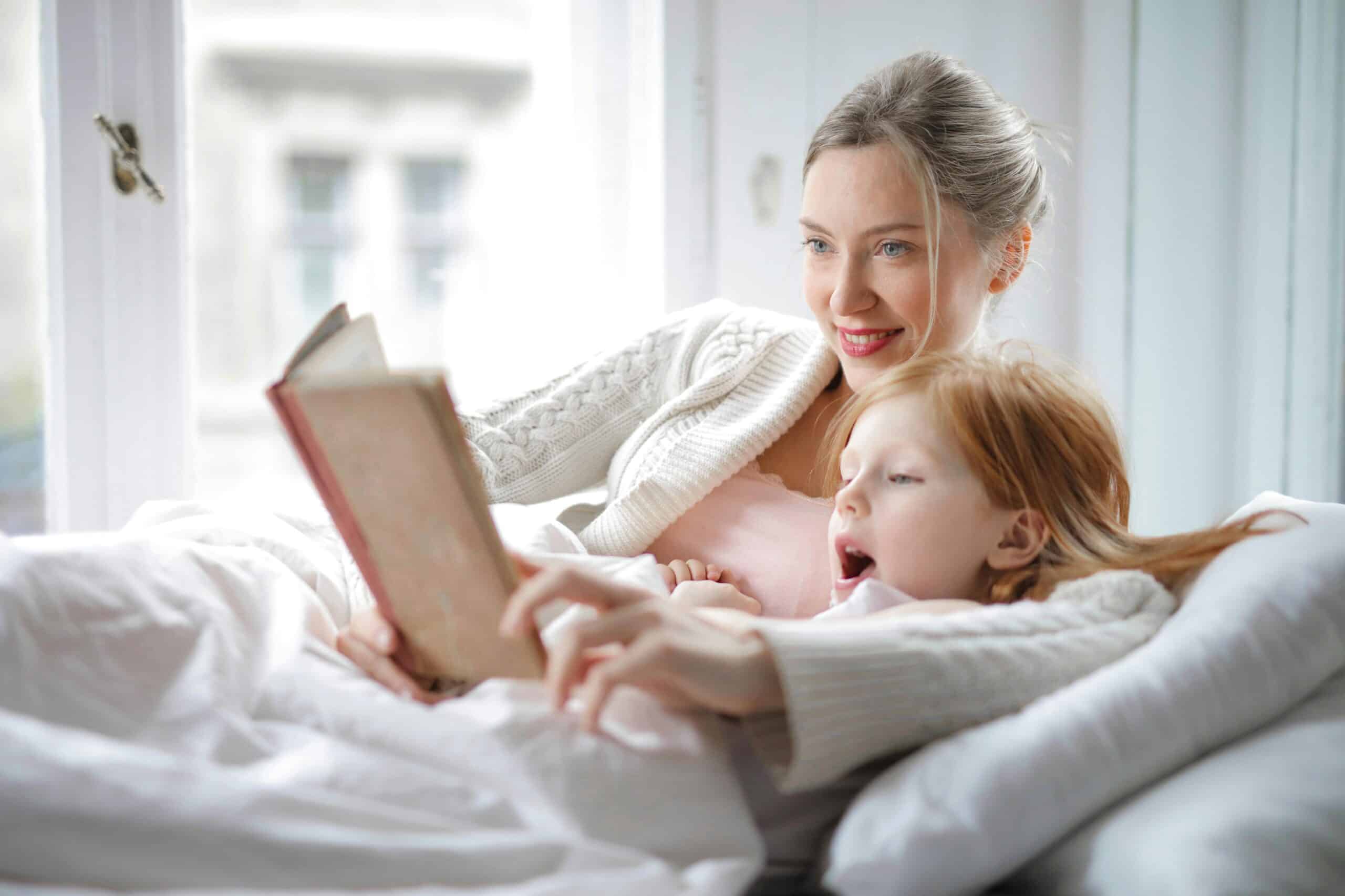 Mother reading to her daughter in bed to establish a healthy sleep routine